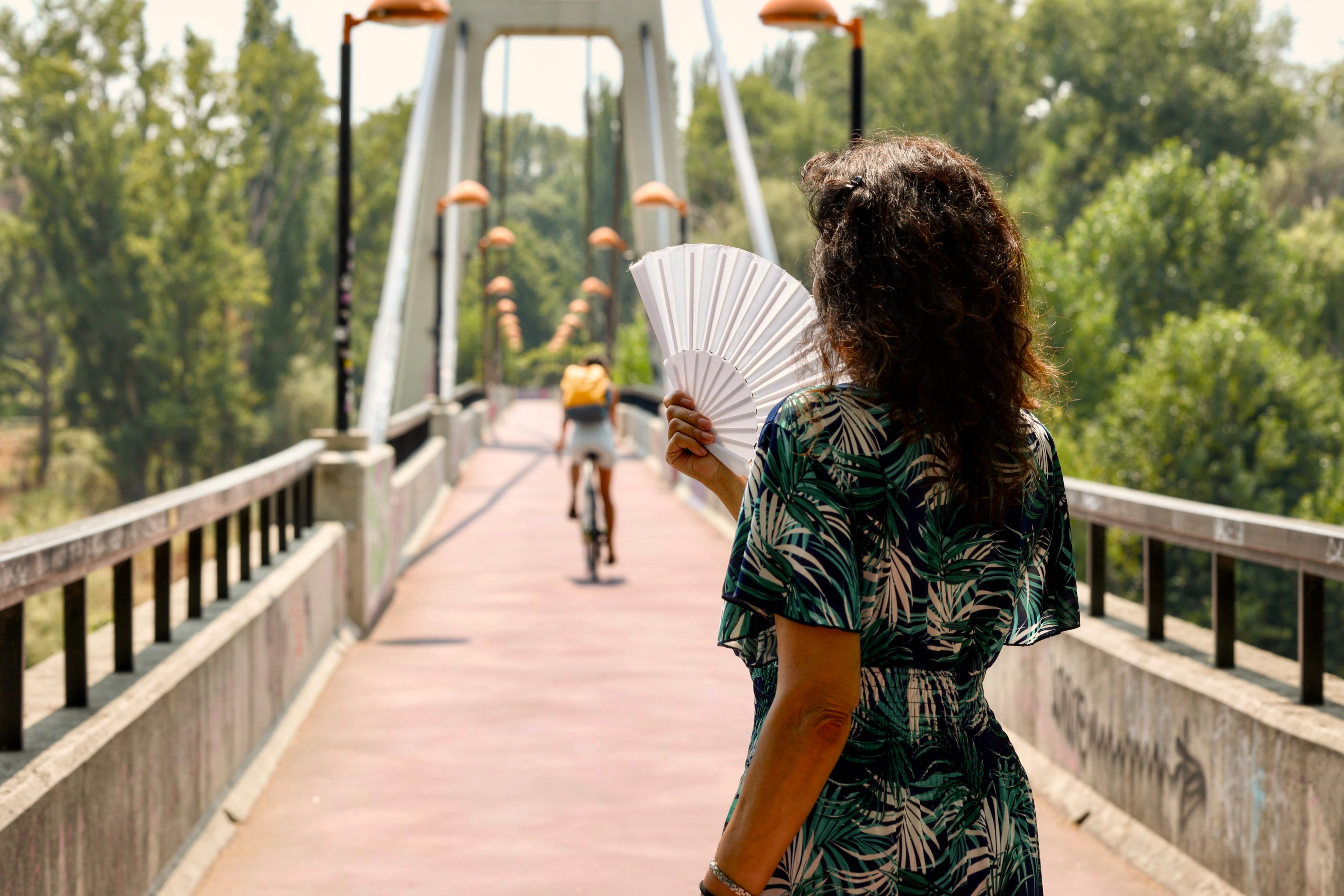 LOGROÑO 16/08/2025.- Una mujer se abanica a su paso por la pasarela sobre el Ebro. La Agencia Estatal de Meteorología (Aemet) prevé para este sábado en La Rioja, cielo poco nuboso y ligero ascenso de las temperaturas. EFE/Raquel Manzanares