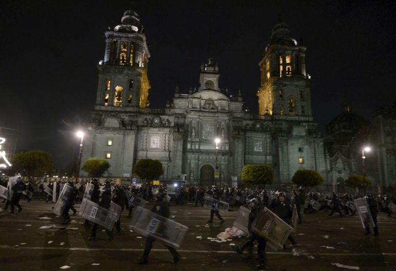 Miembros de la policia federal mexicana toman posiciones durante los enfrentamientos con los manifestantes frente al palacio nacional en la Plaza del Zocalo, sede de la presidencia de la República  