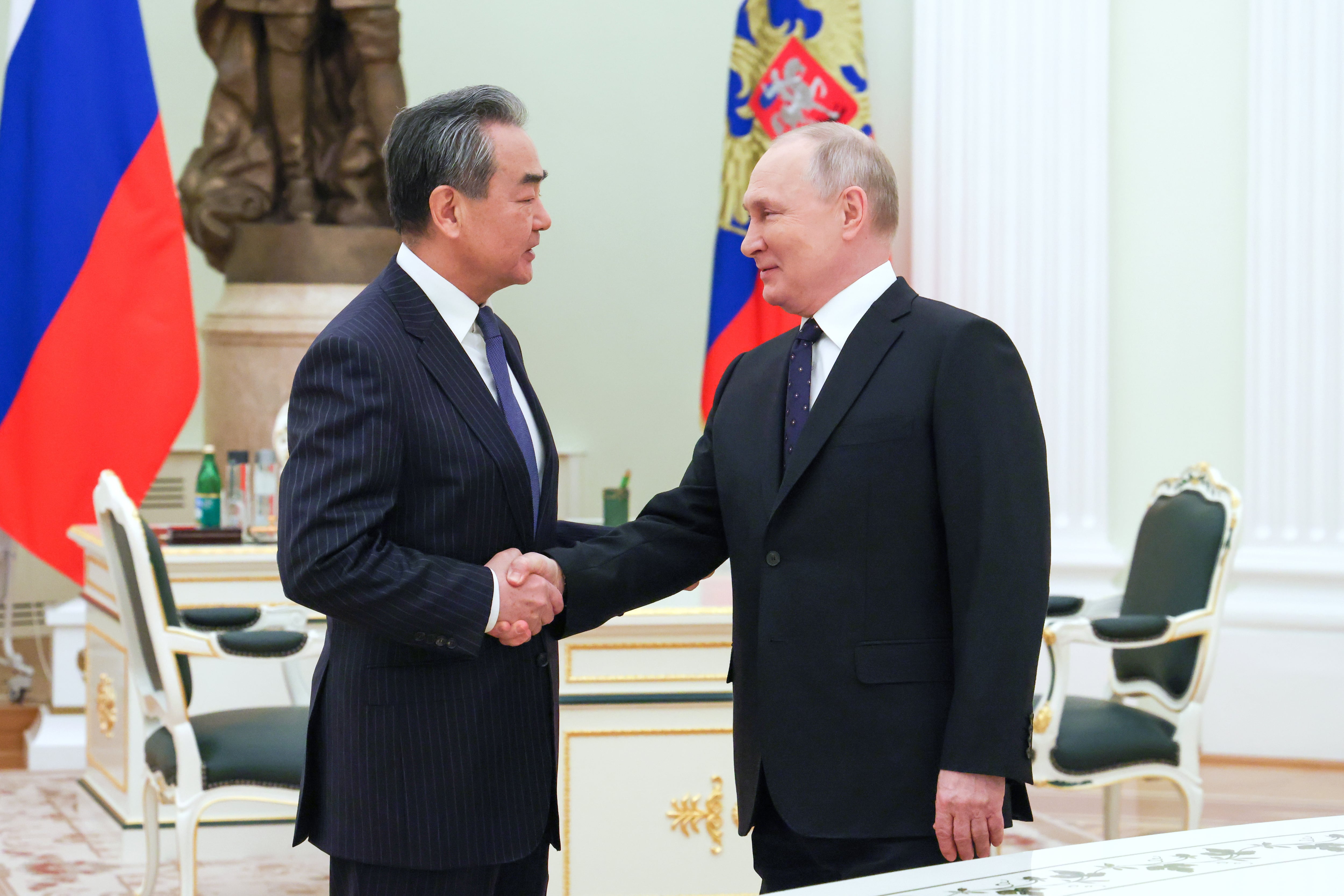 El presidente ruso, Vladímir Putin, saludando al máximo representante de la diplomacia China, Wang Yi