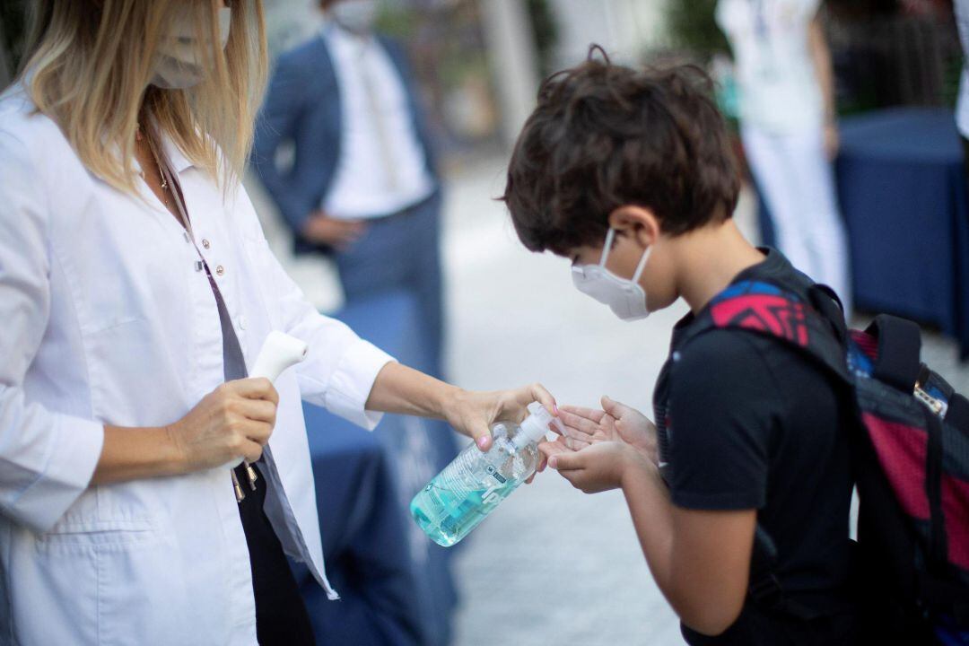 Un niño se desinfecta las manos después de que le tomen la temperatura a la entrada del colegio privado internacional American School of Barcelona, situado en Esplugues de Llobregat (Barcelona), este lunes. Este colegio, con 890 alumnos, es el primero en España que inicia el curso con medidas anticovid. 