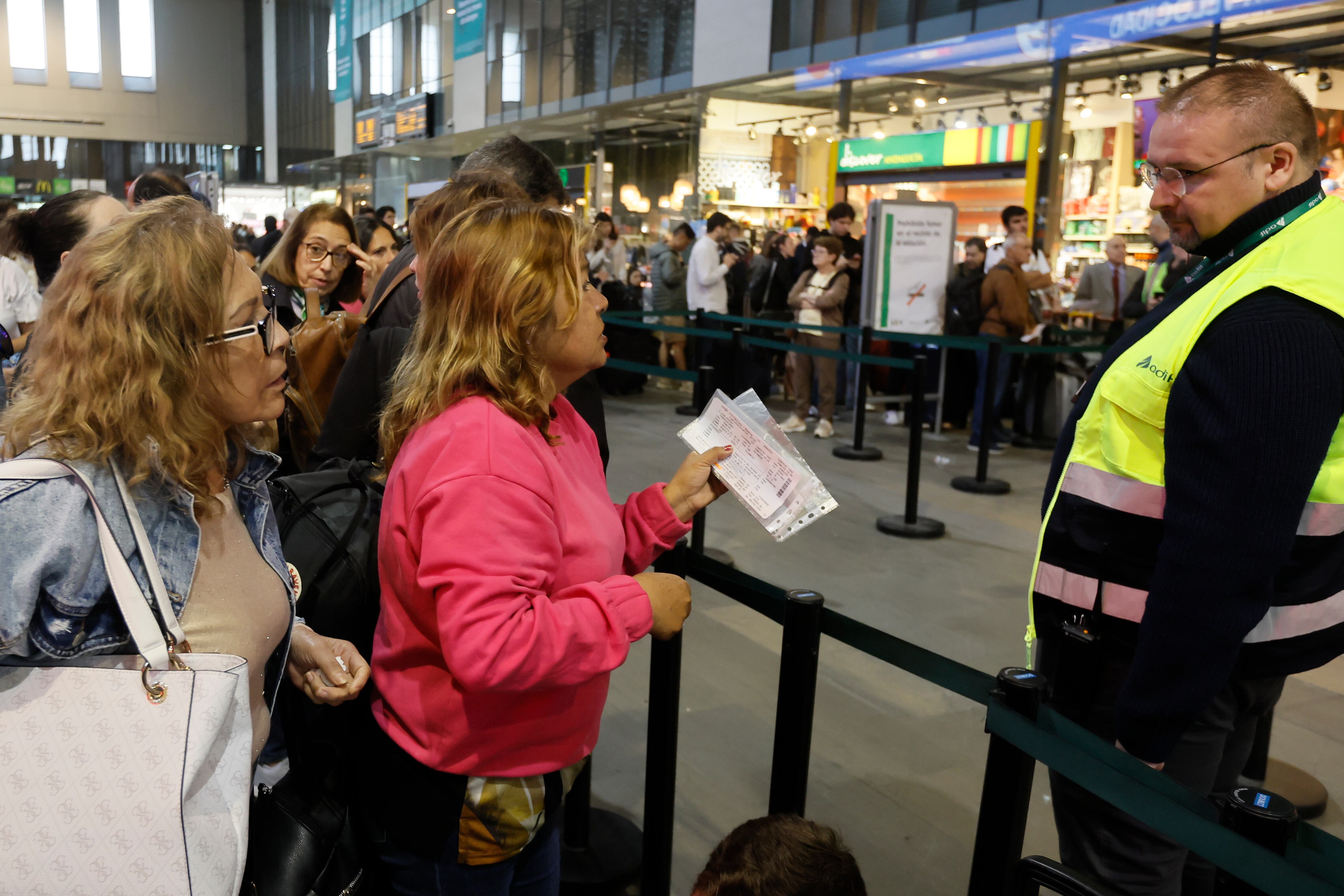 Pasajeros afectados conversan con uno de los empleados mientras aguardan en la Estación de Tren de Santa Justa este lunes tras el robo de cable en cuatro puntos de la provincia de Toledo que ha dejado miles de pasajeros afectados.