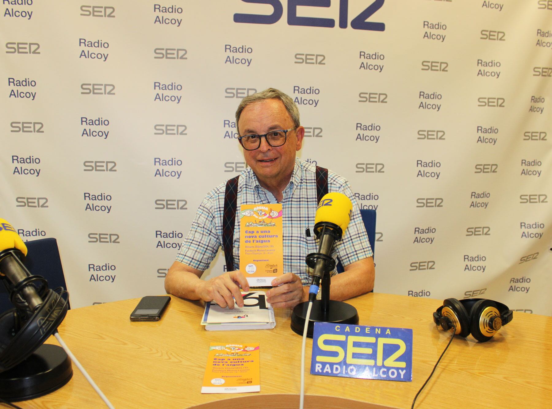 Aleixandre Sanfrancisco, en l'estudi central de Radio Alcoy, mostra el fullet de la jornada on s'aprofitarà per a entregar el premi