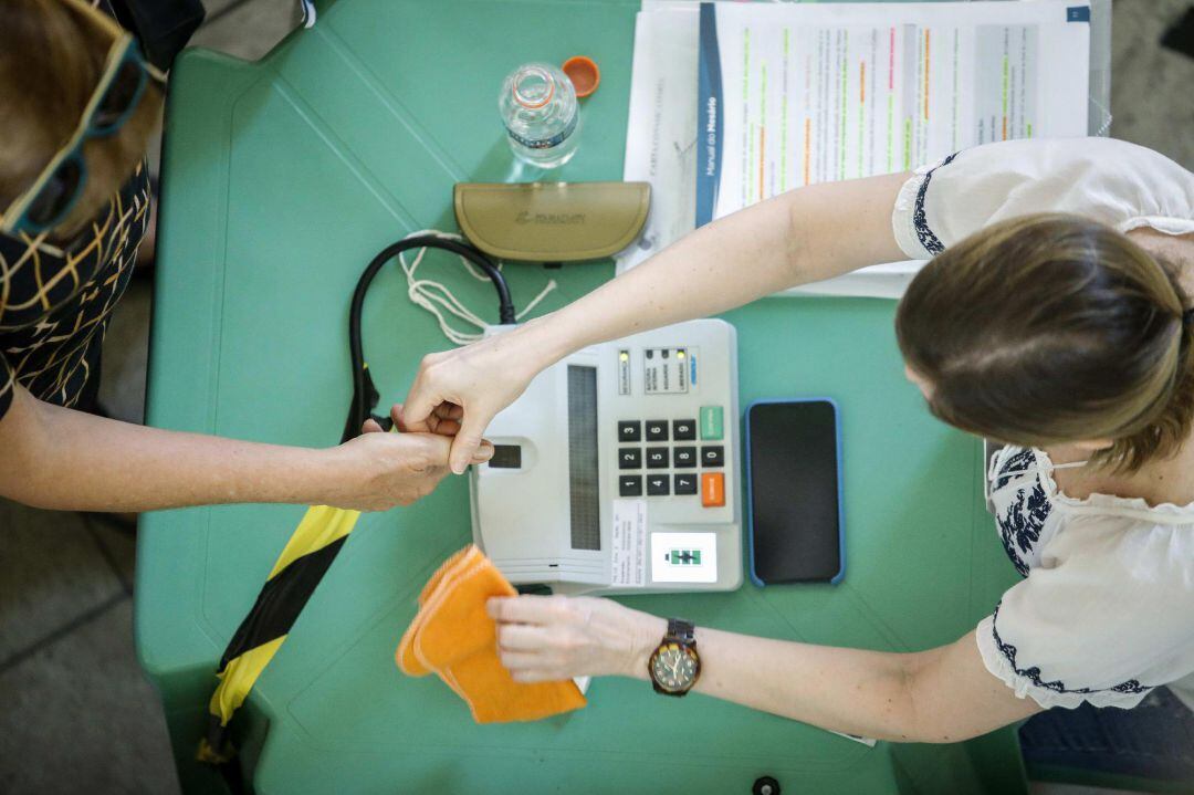 Una mujer se identifica en el lector biométrico antes de votar