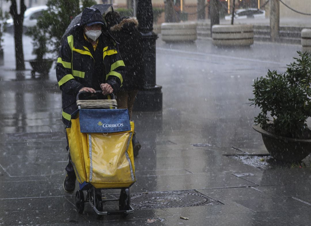 Un repartidor de Correos trabaja bajo la lluvia en una foto de archivo