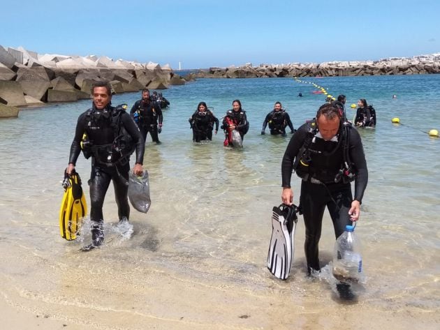 Los voluntarios encargados de la recogida de residuos en el fondo marino, saliendo del agua.