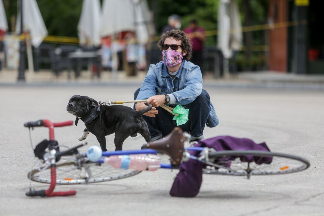 Un hombre con un perro observa a los artistas durante la presentación en El Retiro del Manifiesto Artes de Calle.