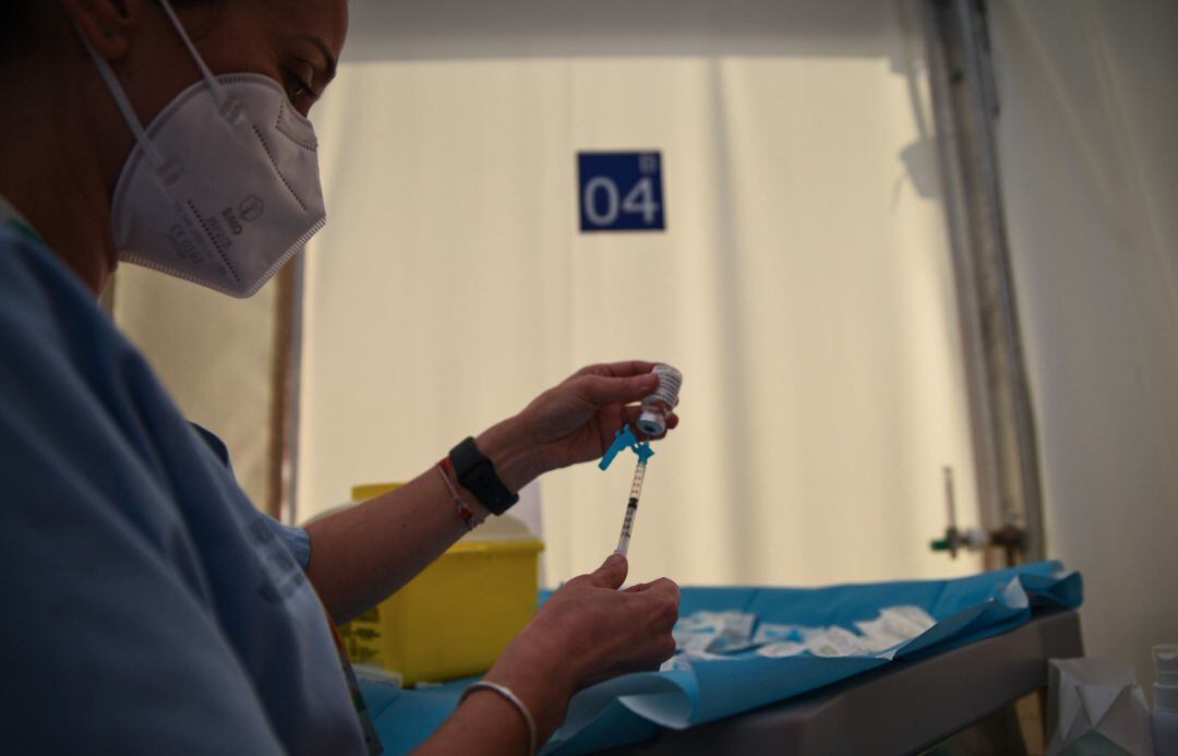 Una profesional sanitaria sostiene una jeringuilla y un vial con la vacuna contra la Covid-19 de AstraZeneca en el Hospital de campaña de La Fe, en València.