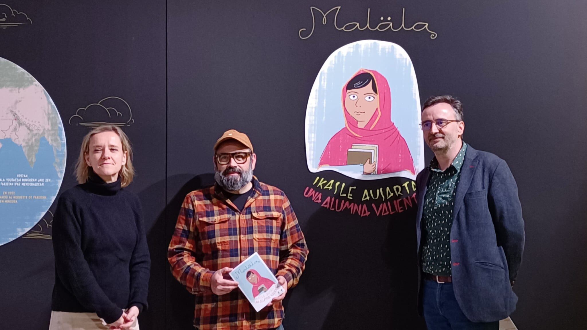 Marta Ibañez, directora de la Casa de la Cultura de Aiete; Asier Iturralde, ilustradoe de la exposición;  y Josemi Beltrán, director del Festival de Cine y Derechos Humanos Donostia, en la sala de la exposición &#039;Malala, una alumna valiente&#039;.