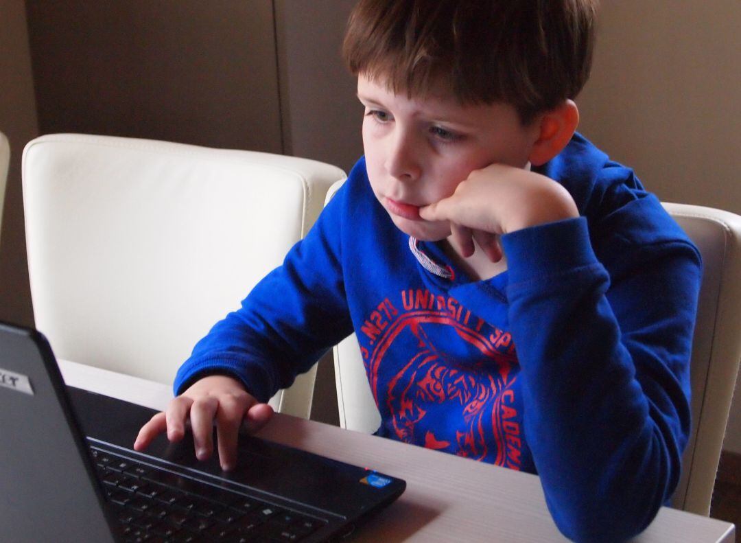 Un nen treballa amb el seu portàtil des de casa