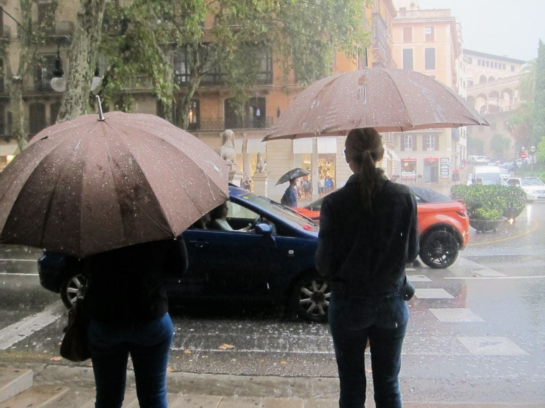 Transeuntes con paraguas se refugian de fuertes lluvias en Palma.