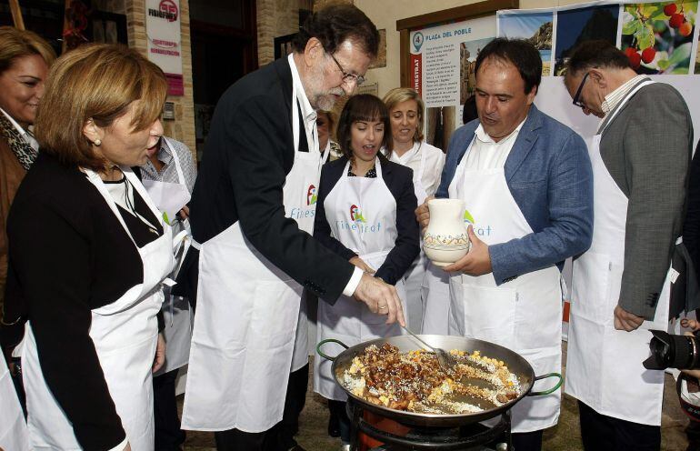 GRA157. FINESTRAT (ALICANTE), 24/010/2015.- El presidente del Gobierno, Mariano Rajoy, ha ayudado a las mujeres de la asociación de amas de casa del pequeño pueblo de Finestrat (Alicante) a preparar una paella de conejo, pollo y garbanzos, tras un acto del PP hoy en la localidad alicantina que será el último al que asista antes de convocar el próximo lunes las elecciones generales del 20 de diciembre. En la foto junto al alcalde de la población, Juan Francisco Pérez. EFE/Morell