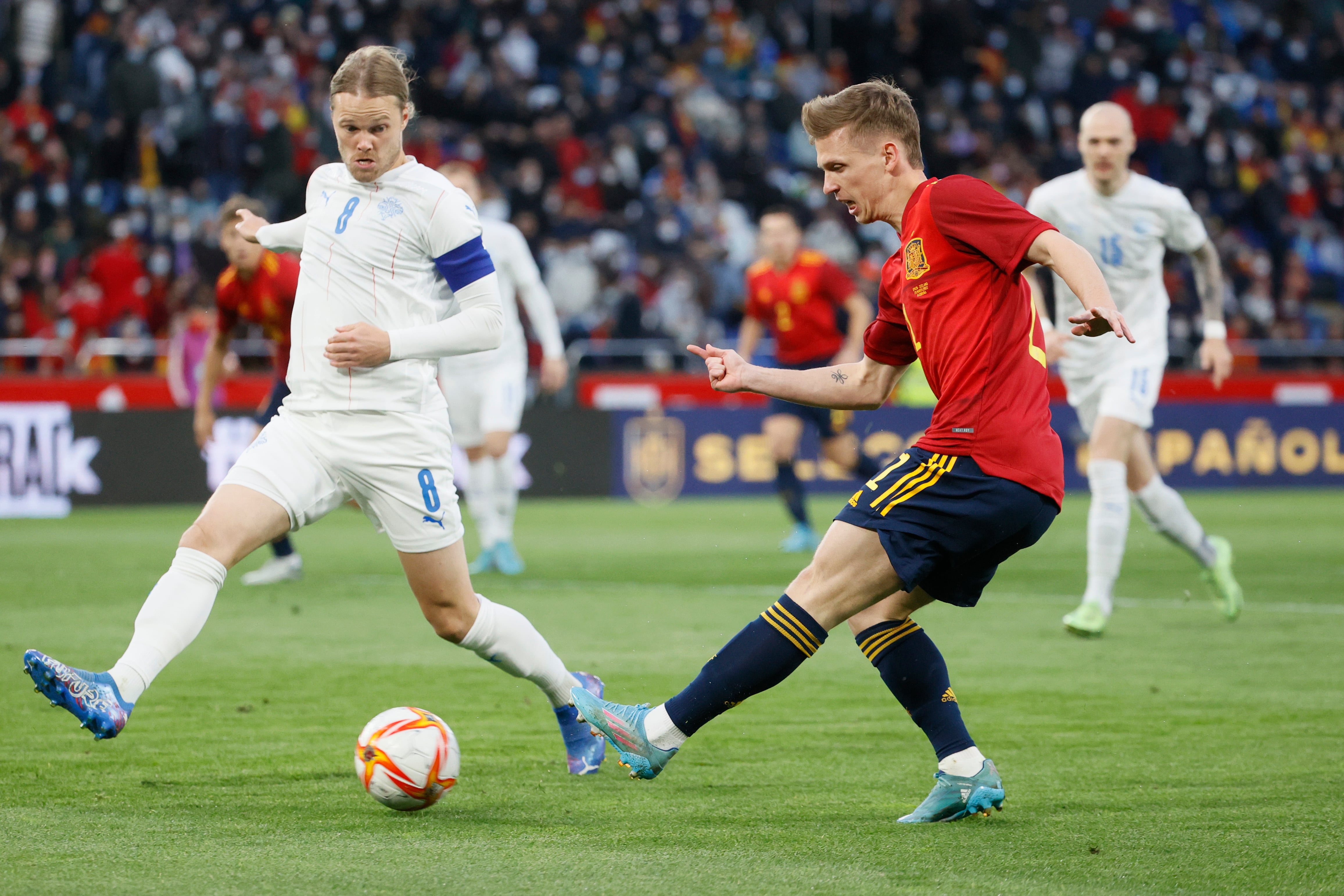 El delantero de la selección española Dani Olmo (d) juega un balón ante Birkir Bjarnason, de Islandia, durante el partido amistoso que disputan este martes en el estadio de Riazor, en A Coruña.