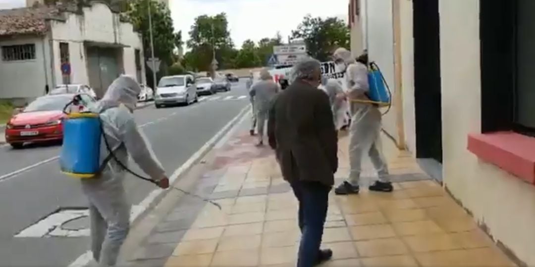 Personas con trajes de fumigar limpian la calle de Estella