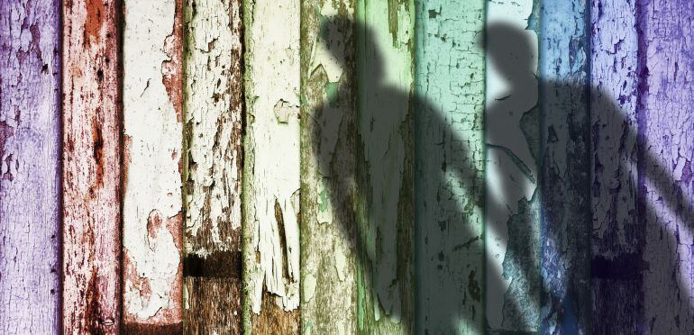La sombra de una pareja gay sobre un muro con la bandera arcoiris. 