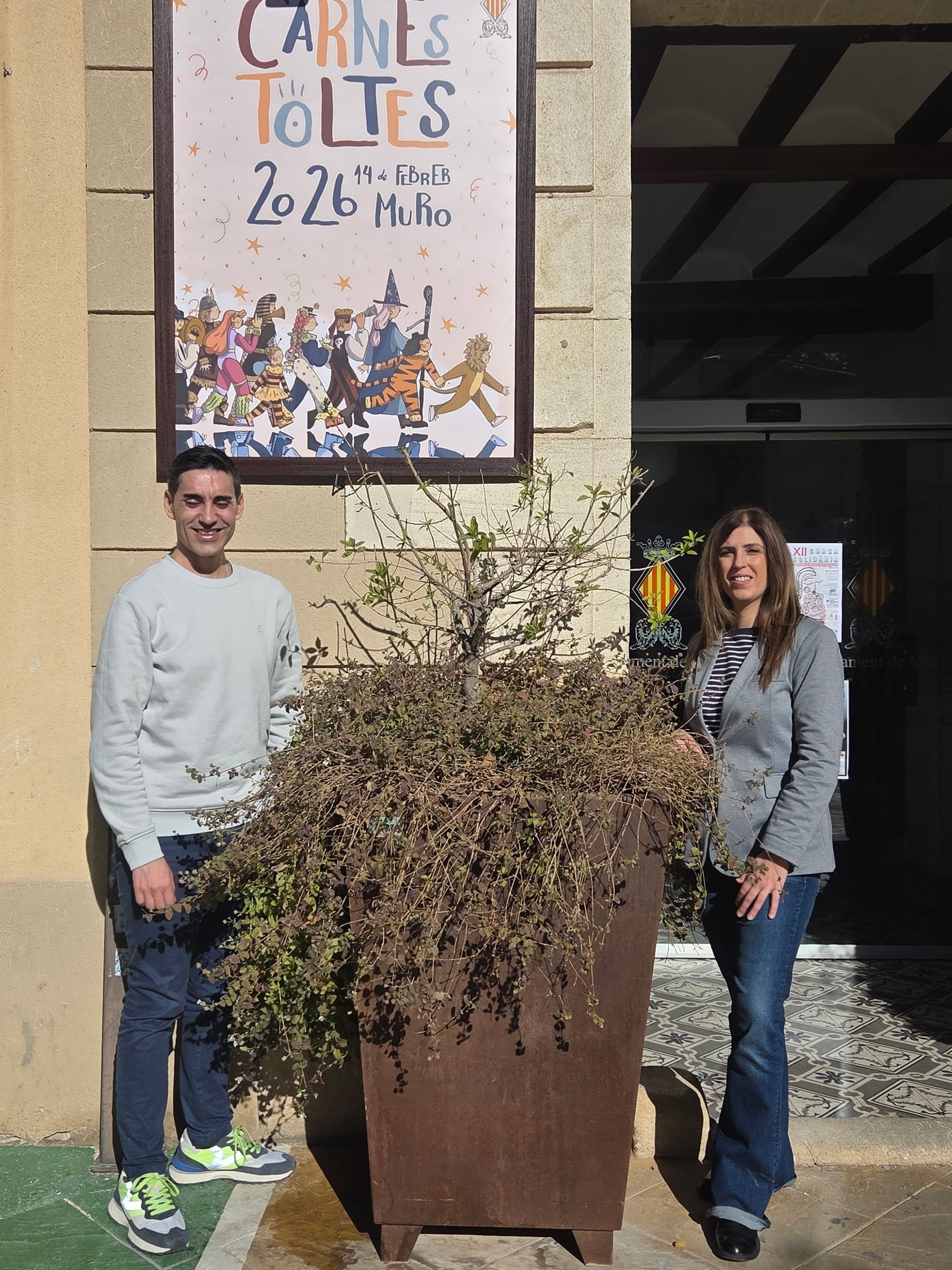 Fernando Picó y Sara Beneyto junto al cartel que anuncia el Carnestoltes murero
