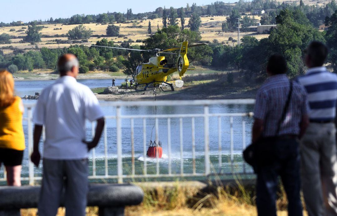 Varias personas observan como los helicópteros toman agua del pantano del Pontón Alto