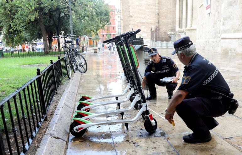 Imagen de archivo de unos agentes de la Policía Local trabajan en la retirada de los patinetes eléctricos de alquiler de la empresa Lime en València