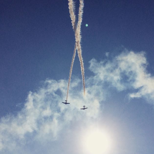 Dos aviones hacen piruetas mientras sobrevuelan el cielo.