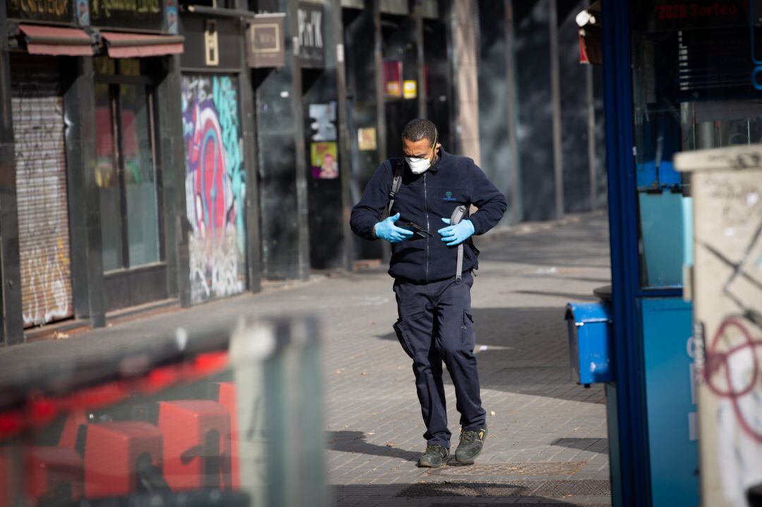 Un hombre protegido con mascarilla y guantes camina por una calle durante el noveno día laborable desde que se decretó el estado de alarma