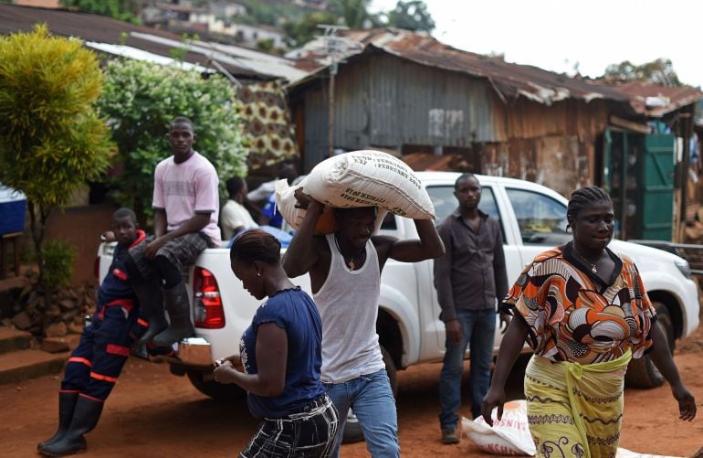 Una familia sometida a cuarentena en Freetown (Liberia) transporta suministros donados por el Programa Mundial de Alimentos