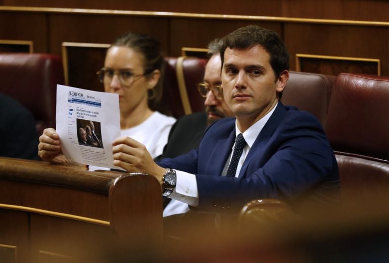 El presidente de Ciudadanos, Albert Rivera, muestra desde su escaño una información de un periódico, esta tarde en el pleno del Congreso