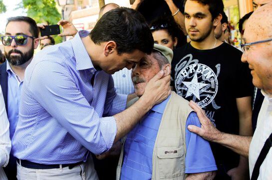 Pedro Sánchez saluda a un anciano en el barrio de Vallecas.