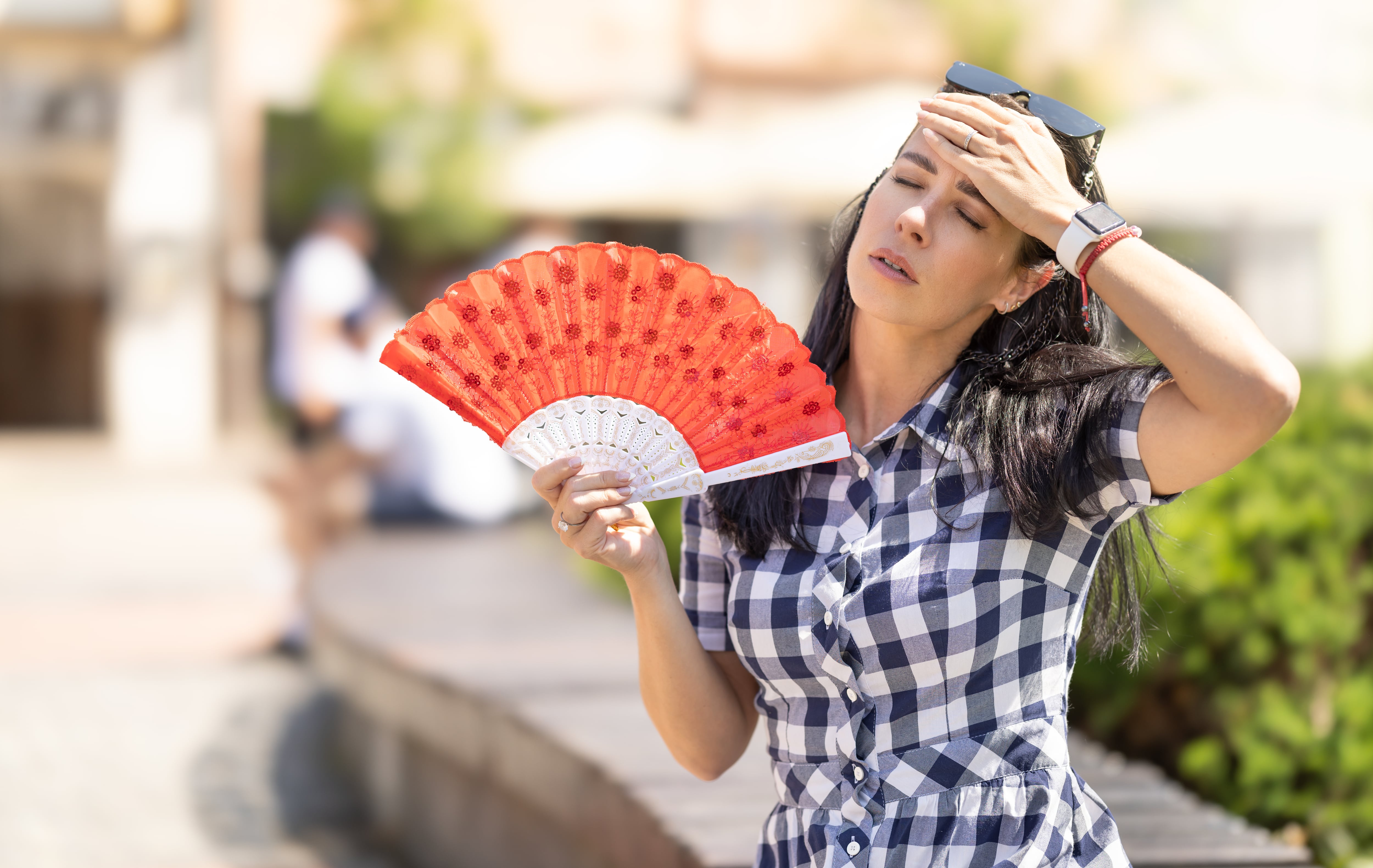 Una mujer usa un abanico para refrescarse de las altas temperaturas.