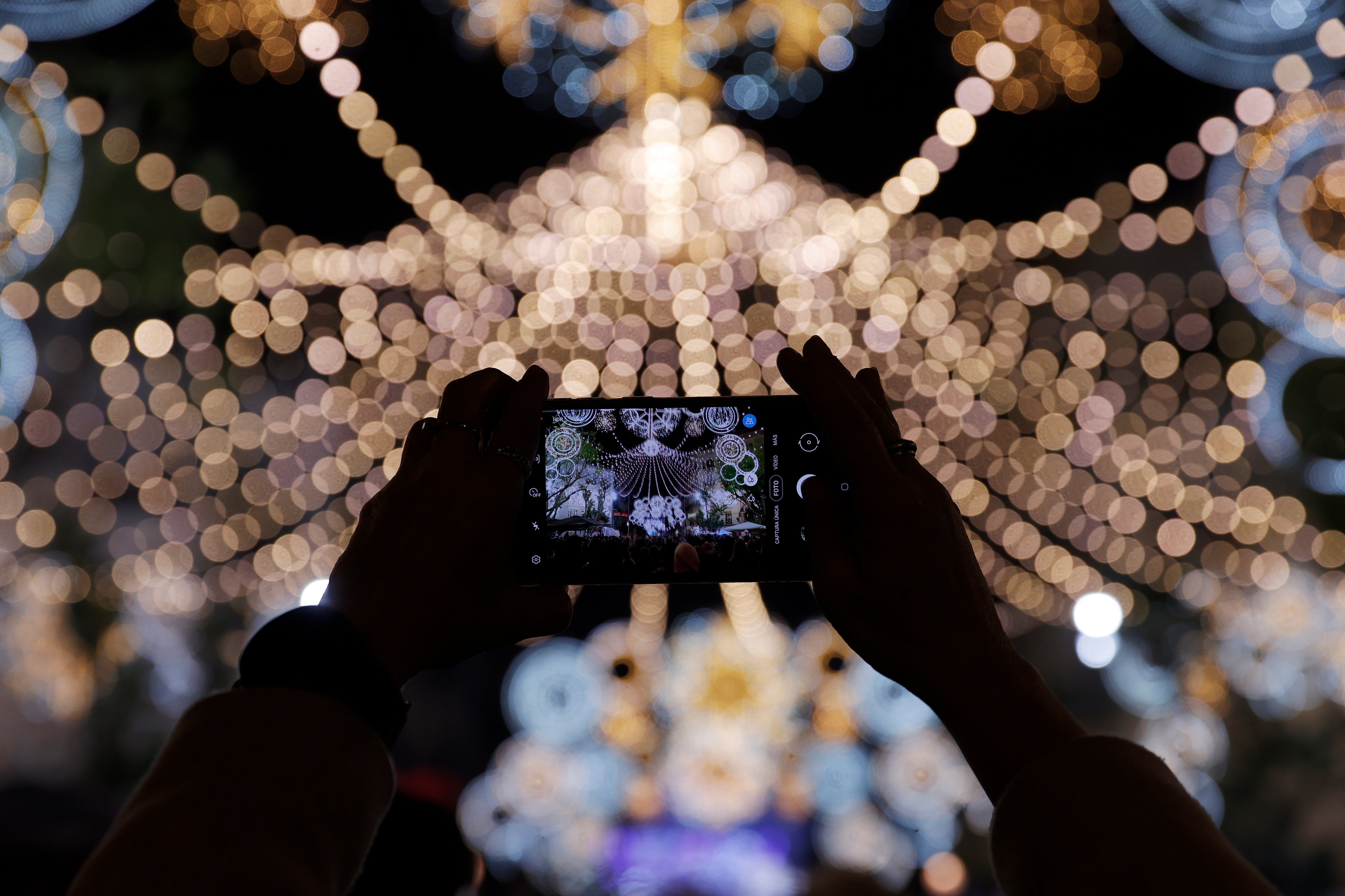 GRAFCVA3659. VALENCIA, 11/03/2022.- Una persona toma una foto de la iluminación de la Falla Cuba-Literato Azorín cuando las fallas del barrio de Ruzafa han encendido este viernes sus tradicionales luces. EFE/Manuel Bruque
