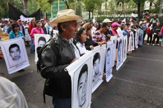 Los manifestantes llevan unos carteles con los rostros de los 43 estudiantes que desaparecieron hace tres meses.