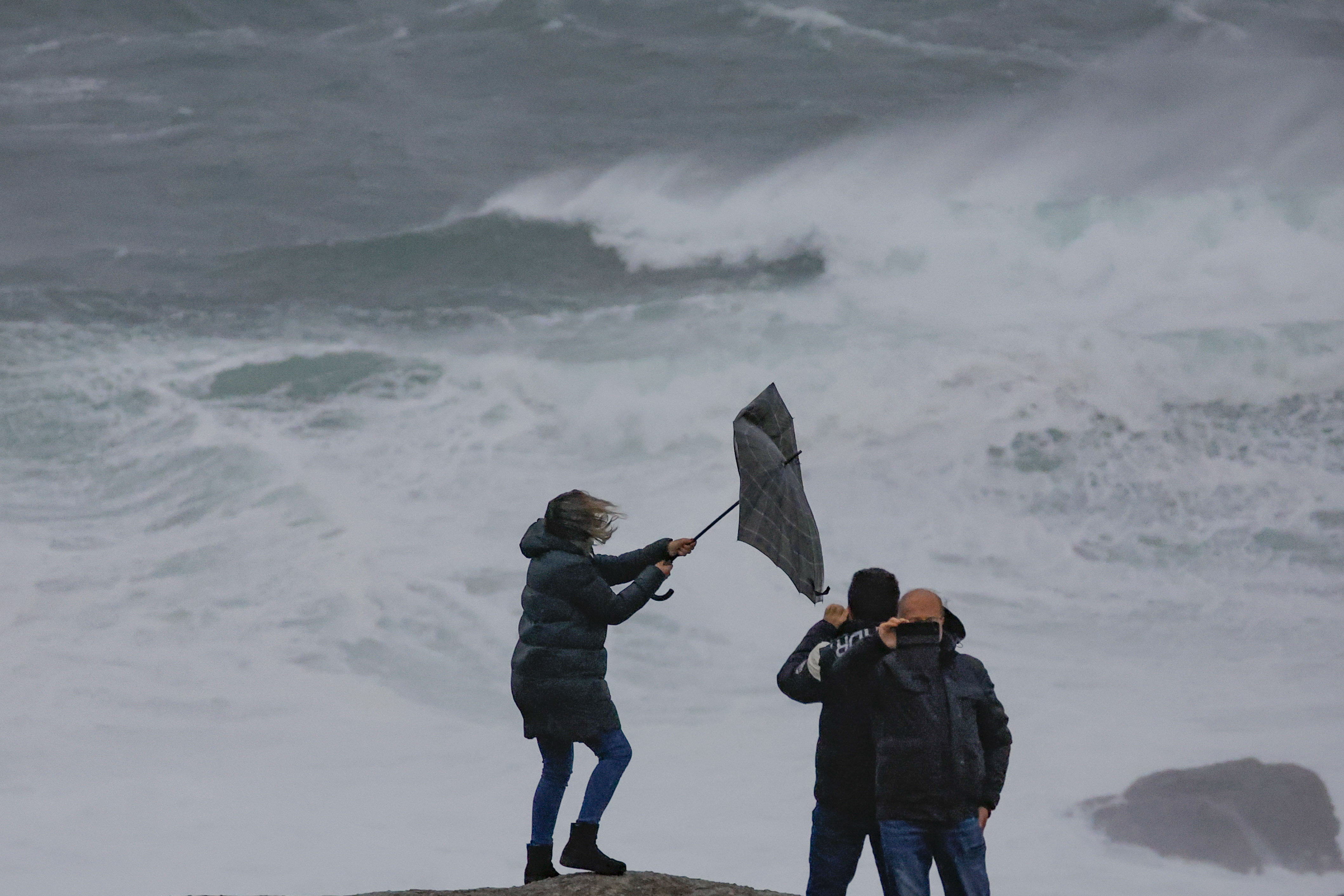 MUXÍA (A CORUÑA), 26/01/2025.-Un grupo de personas en la costa de Muxía, A Coruña, este domingo. Un potente temporal asociado a la borrasca Herminia azotar con fuerza a la península, con lluvias muy intensas y generalizadas, viento con rachas huracanadas por encima de los 20 kilómetros por hora en algunos puntos y aviso rojo en Galicia, donde las olas pueden alcanzar 10 metros de altura. EFE/Lavandeira jr
