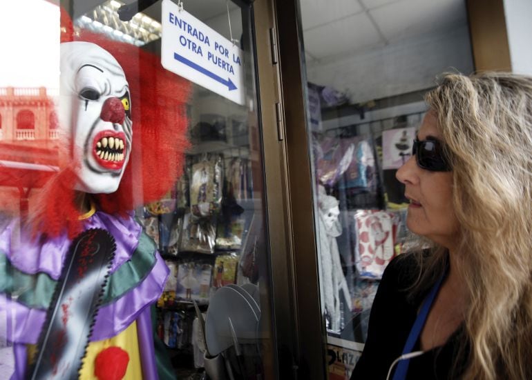 Una mujer observa un dizfraz de payaso diabólico expuesto en una tienda valenciana. El Ayuntamiento de Paterna (Valencia), ha pedido hoy la calma a sus vecinos tras detectar varios episodios de sustos a manos de personas disfrazadas de &quot;payasos diabólicos