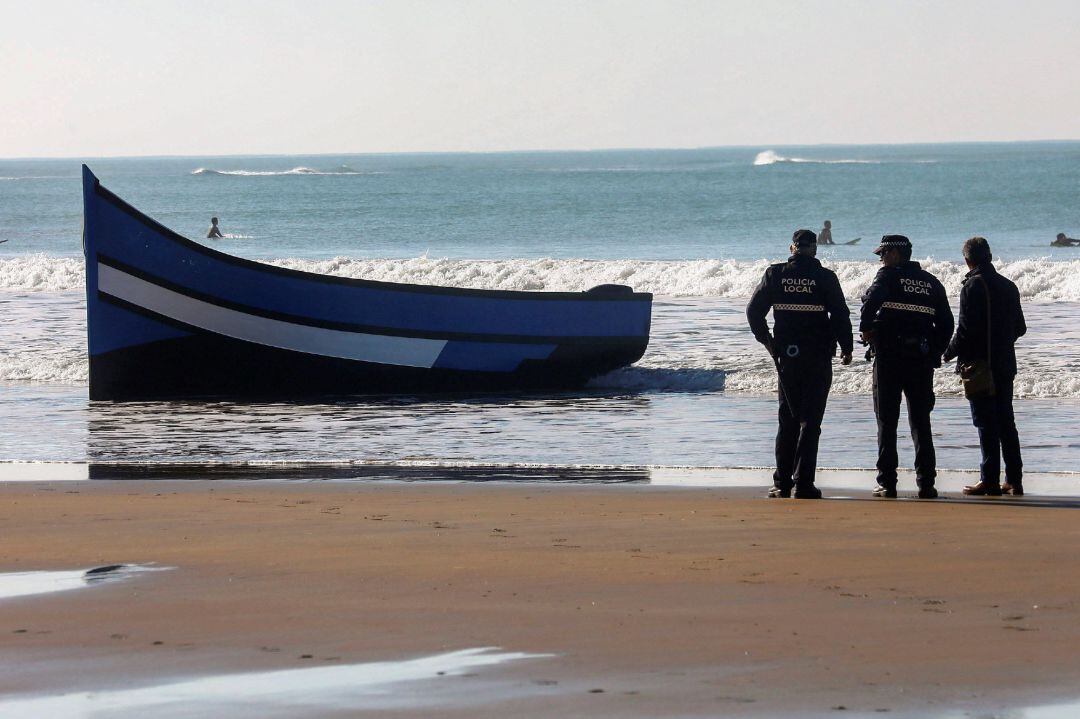 Agentes de la Guardia Civil junto a una patera en la costa 