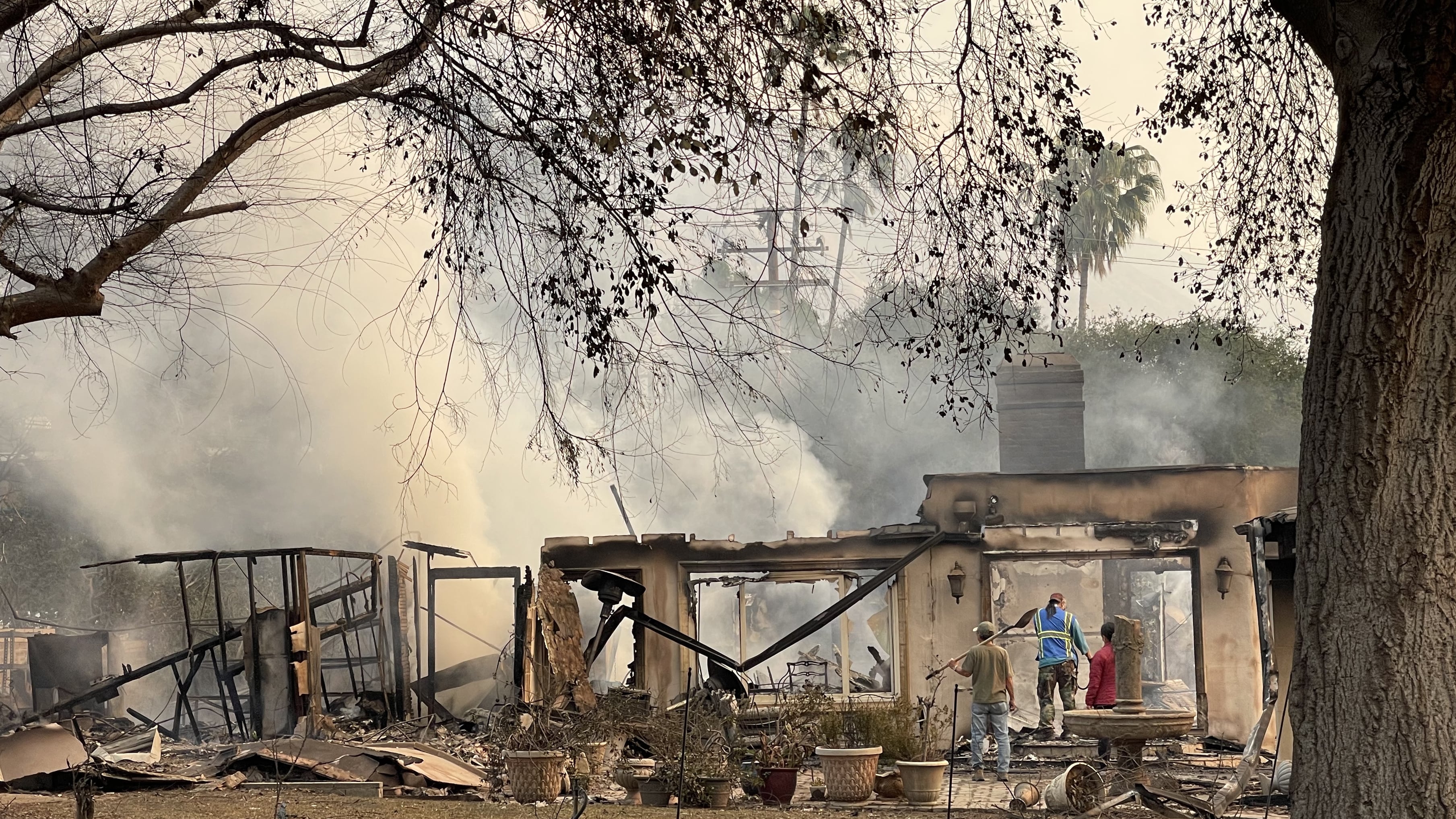 Personas trabajan en el interior de una casa afectada por un incendio este miércoles, en Altadena, California (Estados Unidos)