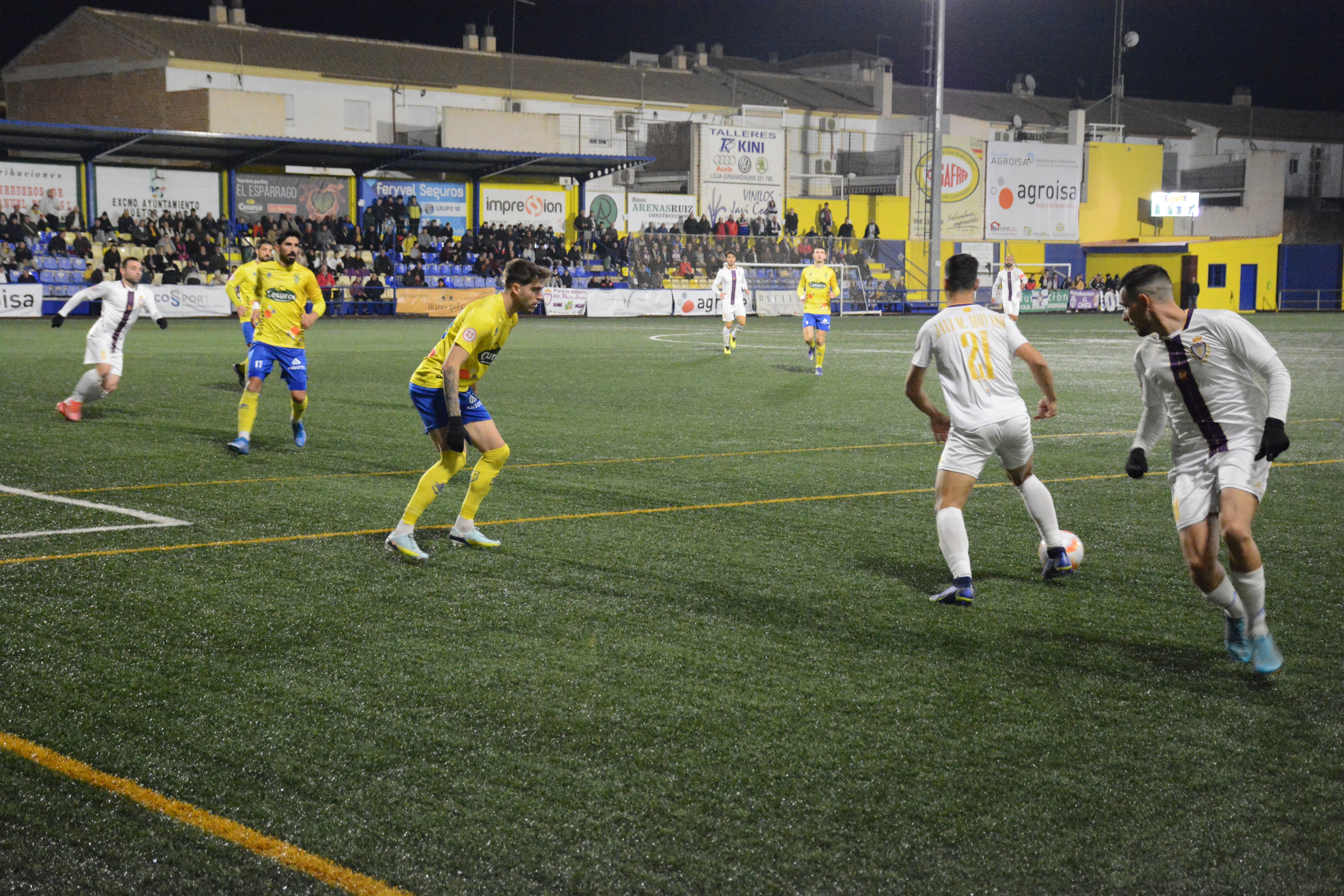 El jugador Javi Moyano junto a Adri Paz, jugadores del Real Jaén junto a un defensa local  en una jugada durante el partido