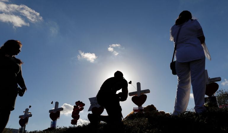 Un hombre reza frente a una cruz durante el homenaje a las víctimas del tiroteo.