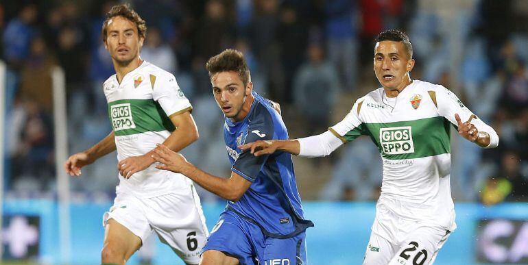 El centrocampista del Getafe Pablo Sarabia (c) controla el balón ante los jugadores del Elche, Pedro Mosquera (i) y el francés Faycal Fajr durante el partido correspondiente a la undécima jornada de Liga de Primera división que disputan en el estadio Coli