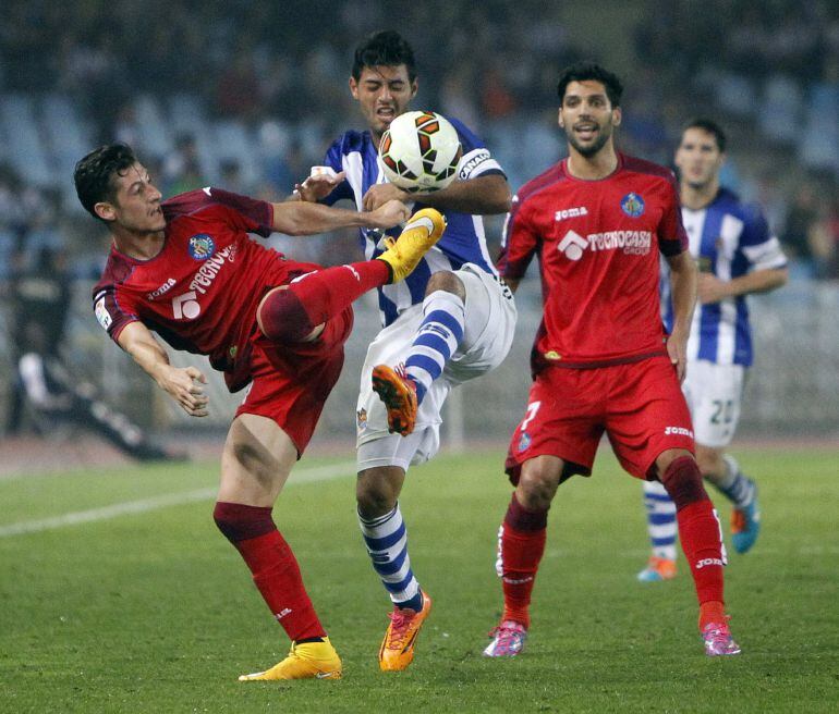 GRA359. SAN SEBASTIÁN, 20/10/2014.- El delantero mexicano de la Real Sociedad, Carlos Vela (c), intenta superar la entrada del defensa del Getafe, Sergío Escudero (i), durante el encuentro correspondiente a la octava jornada de primera división, que han disputado esta noche en el estadio de Anoeta. EFE/Javier Etxezarreta.