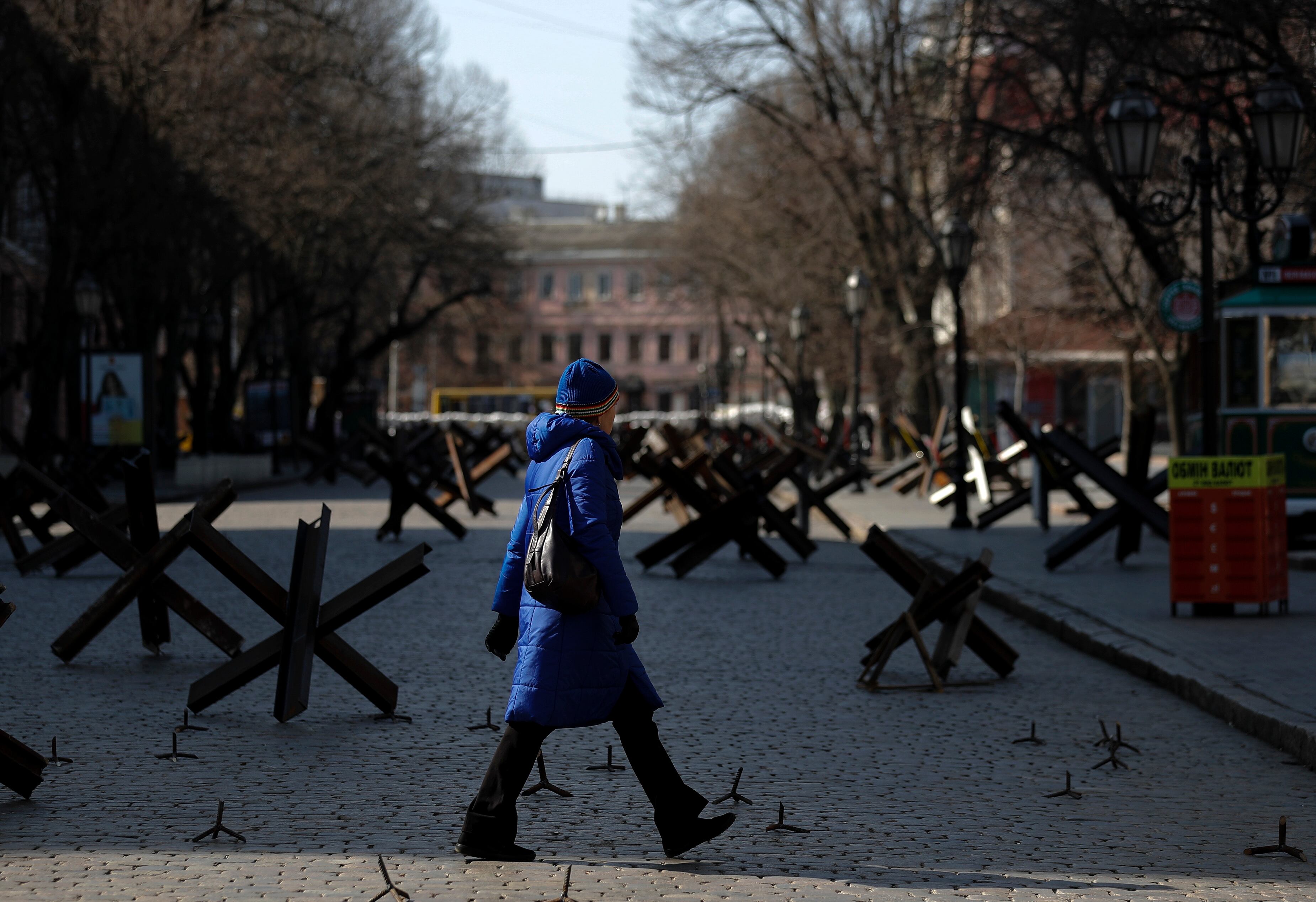 Una mujer cruza una calle en el centro de la ciudad de Odesa, bloqueada con defensas anti tanque.