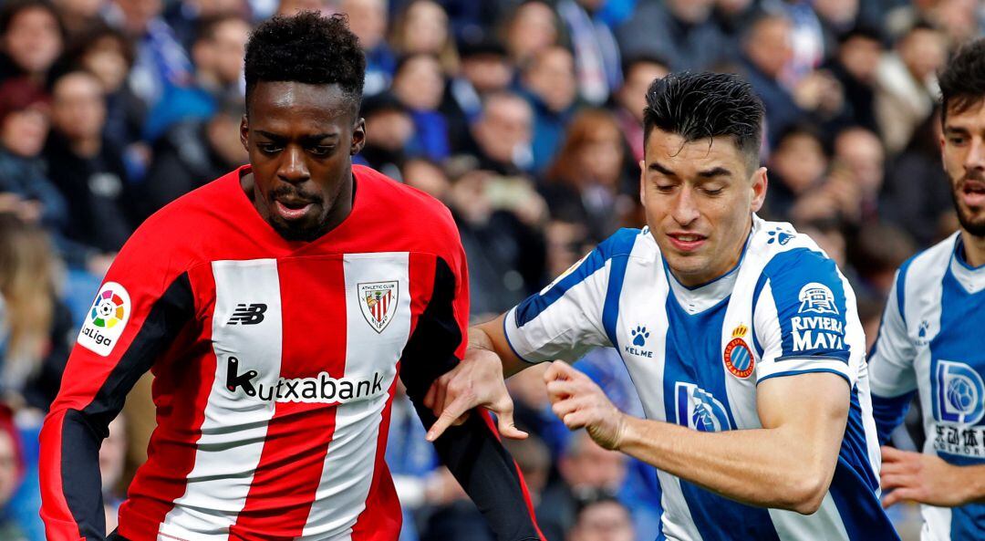 El delantero del Athletic de Bilbao Iñaki Williams (i), y el jugador del Espanyol Marc Roca (d), durante el partido de LaLiga Santander correspondiente a la jornada 21 disputado este sábado en el RCDE Stadium