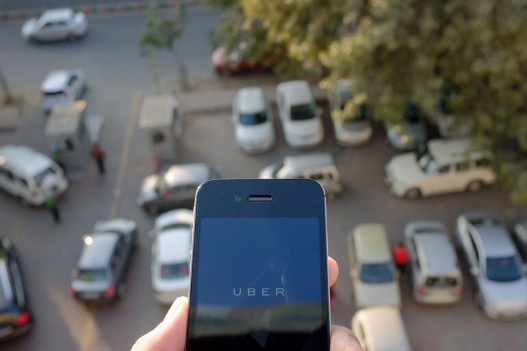 The Uber smartphone app, used to book taxis using its service, is pictured over a parking lot in the Indian capital New Delhi on December 7, 2014. An Uber taxi driver allegedly raped a 25-year-old passenger in the Indian capital before threatening to kill her, police said December 7, in a blow to the company&#039;s safety-conscious image. AFP PHOTO/TENGKU BAHAR