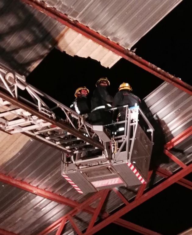 Los bomberos sujetando una de las numerosas planchas desprendidas por el viento.