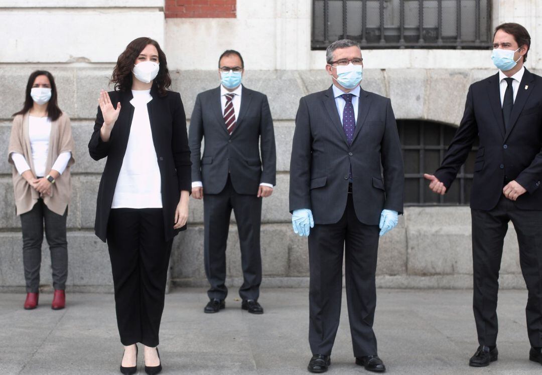 La presidenta de la Comunidad de Madrid, Isabel Díaz Ayuso (2i), guarda un minuto de silencio antes de su reunión en la Real Casa de Correos con el presidente de la Federación Madrileña de Municipios, Guillermo Hita (2d).