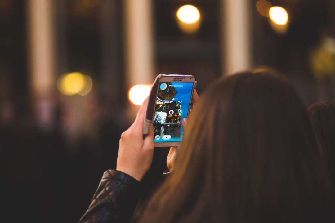 Una chica mira la pantalla de su teléfono móvil.