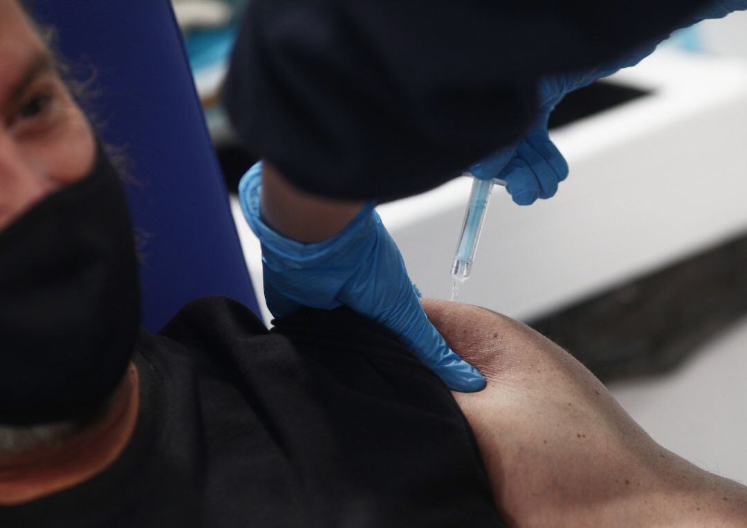 Una enfermera vacuna a un hombre.