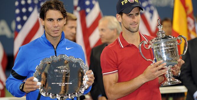 El tenista serbio Novak Djokovic (d) sostiene el trofeo de campeón después de vencer al español Rafael Nadal (i), con el platillo de subacmpeón