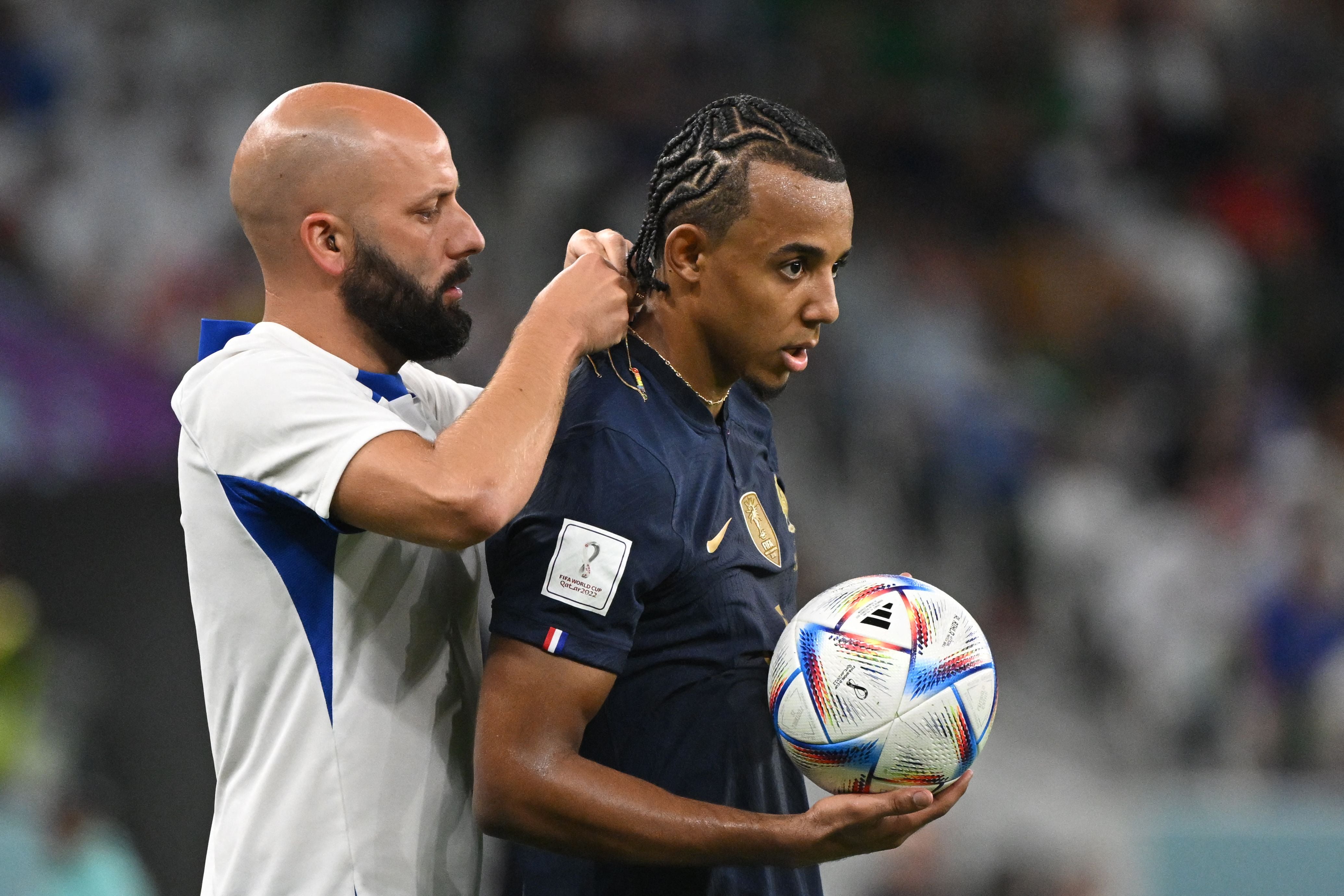 Un ayudante de la selección francesa le quita el collar de oro a Jules Koundé