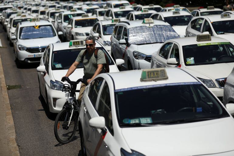 Un ciclista trata de atravesar los taxis en el Paseo de la Castellana.
