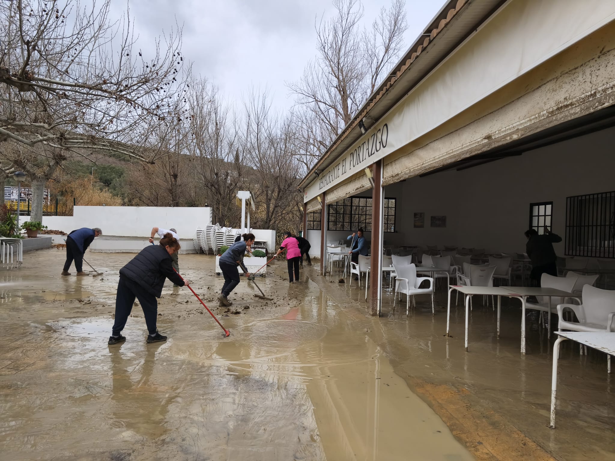Varias vecinas limpian una zona afectada por las inundaciones en los Puentes de Jaén.