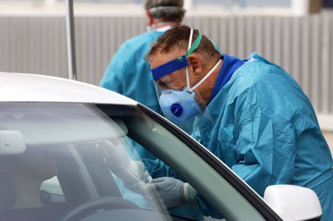 Un sanitario realiza un test PCR a través de la ventanilla de un coche