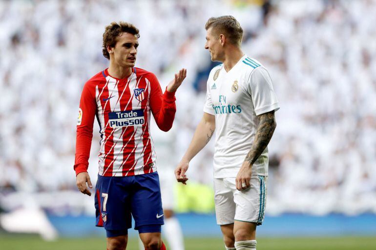 El delantero francés del Atlético de Madrid, Antoine Griezmann, conversa con el centrocampista alemán del Real Madrid, Toni Kroos.